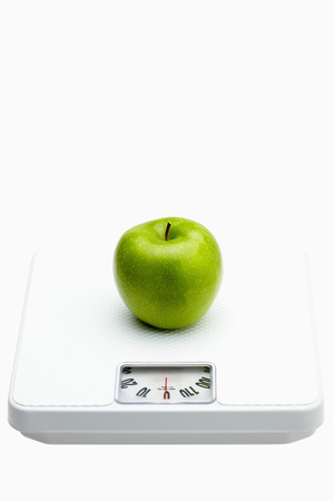 Green apple on a weighing scaleの写真素材