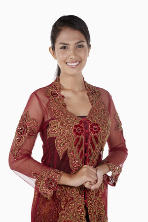 Woman in baju kebaya smiling with her hands claspedの写真素材