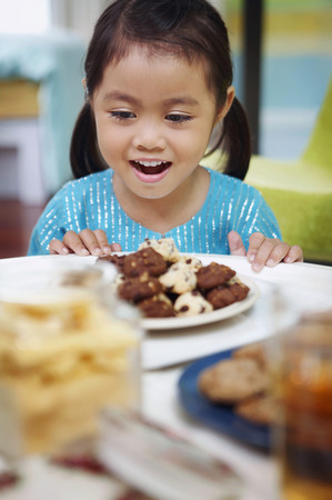 Girl smiling while looking at a plate of cookiesの写真素材