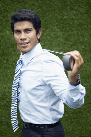 Young Asian businessman holding a golf clubの写真素材