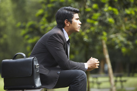 Young Asian businessman sitting on a park benchの写真素材