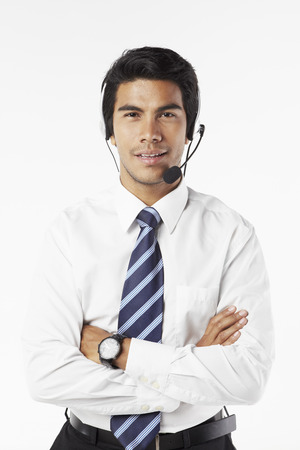 Young businessman wearing headset with arms crossedの写真素材