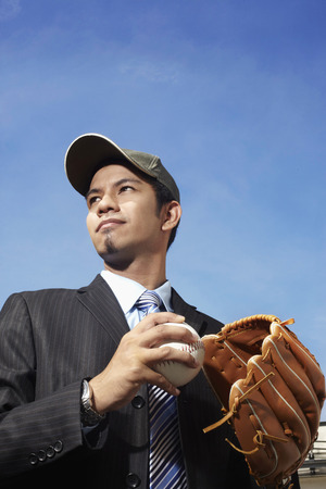 Young businessman with a cap equipped with baseball glove and ballの写真素材