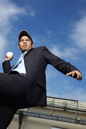 Young businessman about to throw baseballの写真素材