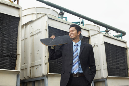 Young businessman holding a skateboard の写真素材