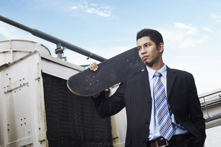 Young businessman holding a skateboard の写真素材