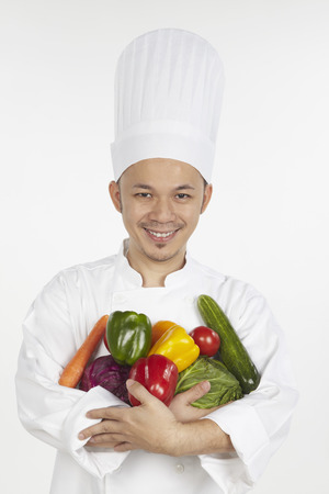 Asian chef with an armful of vegetablesの写真素材
