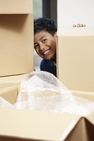 Boy hiding behind cardboard boxesの写真素材