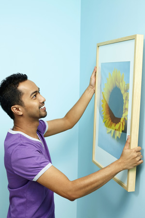 Man putting up new painting on wallの写真素材