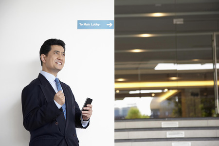 Businessman with smart phone in hand, cheeringの写真素材