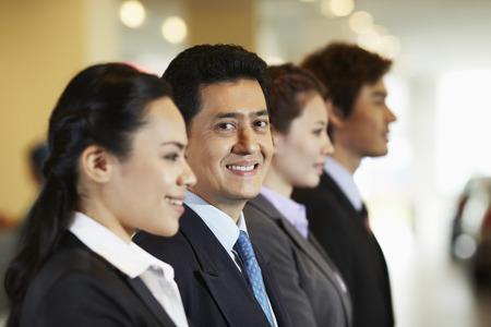 Business people standing in a row ready to greet clientsの写真素材