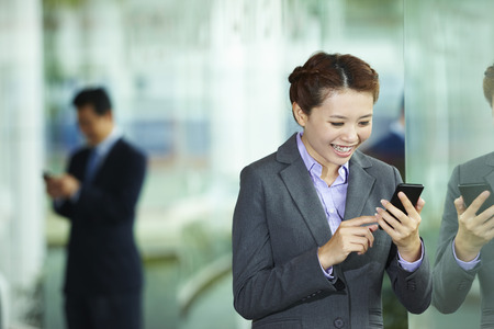 Businesswoman smiling while reading text messageの写真素材