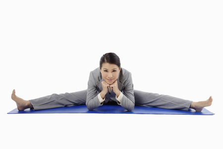 Mid adult businesswoman doing a wide angle seated forward bendの写真素材