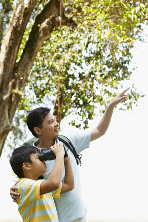 Father teaching son how to use binocularsの写真素材