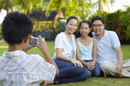 Boy taking picture of his family with a cameraの写真素材