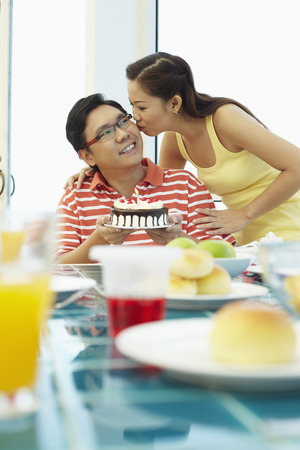 Woman giving man a birthday kissの写真素材