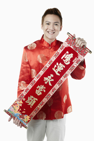 Man in traditional clothing holding banner with Chinese New Year greetingsの写真素材