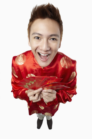 Man in traditional clothing holding red packetsの写真素材