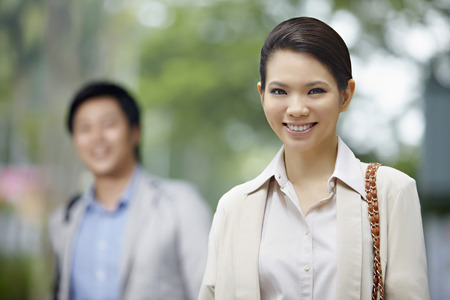Businesswoman smiling while man stands in the backgroundの写真素材