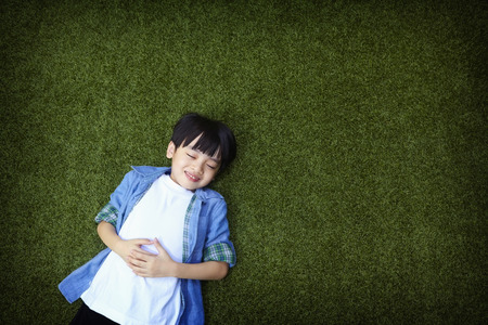 Boy lying down on the grassの写真素材