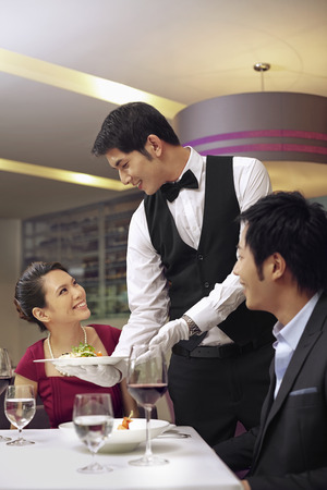 Waiter serving food to customersの写真素材