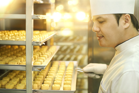 Pastry chef inspecting a tray of biscuitsの写真素材