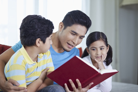 Father reading a book with his childrenの写真素材