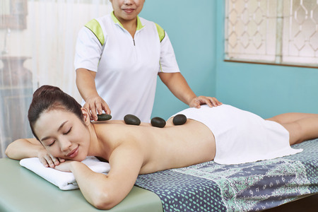 Massage stone on a young woman's backの写真素材