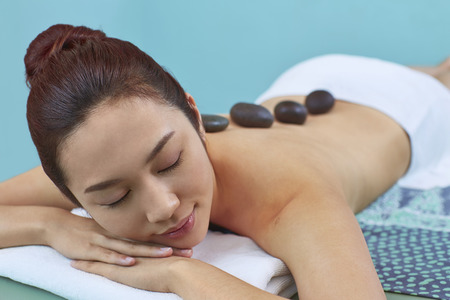 Massage stone on a young woman's backの写真素材