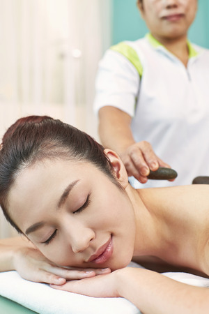 Massage stone on a young woman's backの写真素材