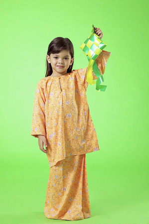 Young Malay girl in baju kurung holding ketupatの写真素材