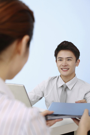 Businesswoman passing document to businessmanの写真素材