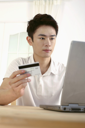 Man holding credit card while using laptopの写真素材