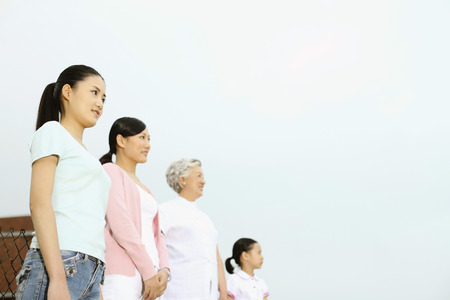 Three women and girl standing in a row, looking awayの写真素材