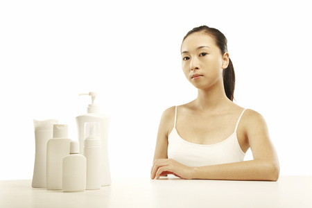 Woman sitting with beauty products on the tableの写真素材