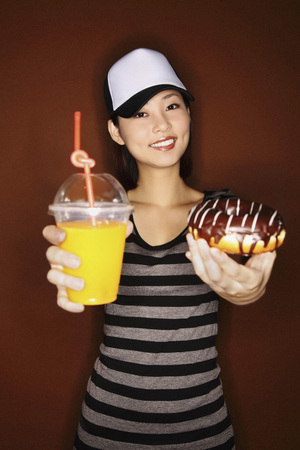 Woman holding doughnut and orange juiceの写真素材