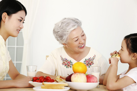 Woman, senior woman and girl having breakfast togetherの写真素材