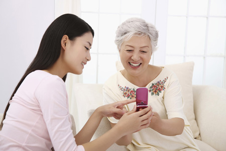 Woman showing senior woman text message on the phoneの写真素材