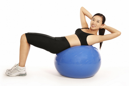 Young woman doing sit-ups on fitness ballの写真素材