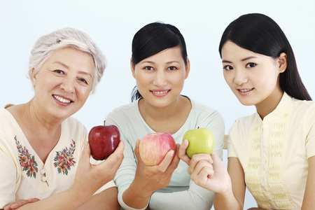 Three women holding apple and smilingの写真素材