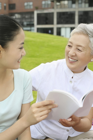 Woman and senior woman reading bookの写真素材