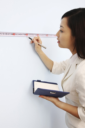 Businesswoman taking down measurements into organizerの写真素材