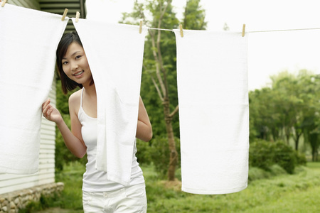 Woman standing from behind towel hanging on clotheslineの写真素材