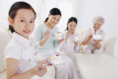 Three women and girl enjoying a slice of birthday cakeの写真素材