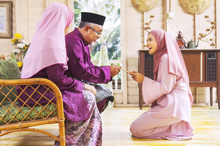 Senior muslim man receiving green envelope from his daughter during Eid al-Fitrの写真素材