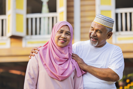 Senior couple standing in front of wooden houseの写真素材