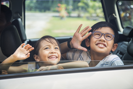 Children in the car looking up and wavingの写真素材