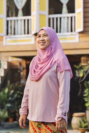 Senior woman standing in front of wooden houseの写真素材