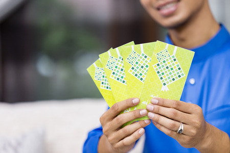 Muslim man holding green envelopes