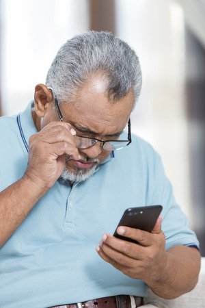 Senior man looking at his phoneの写真素材